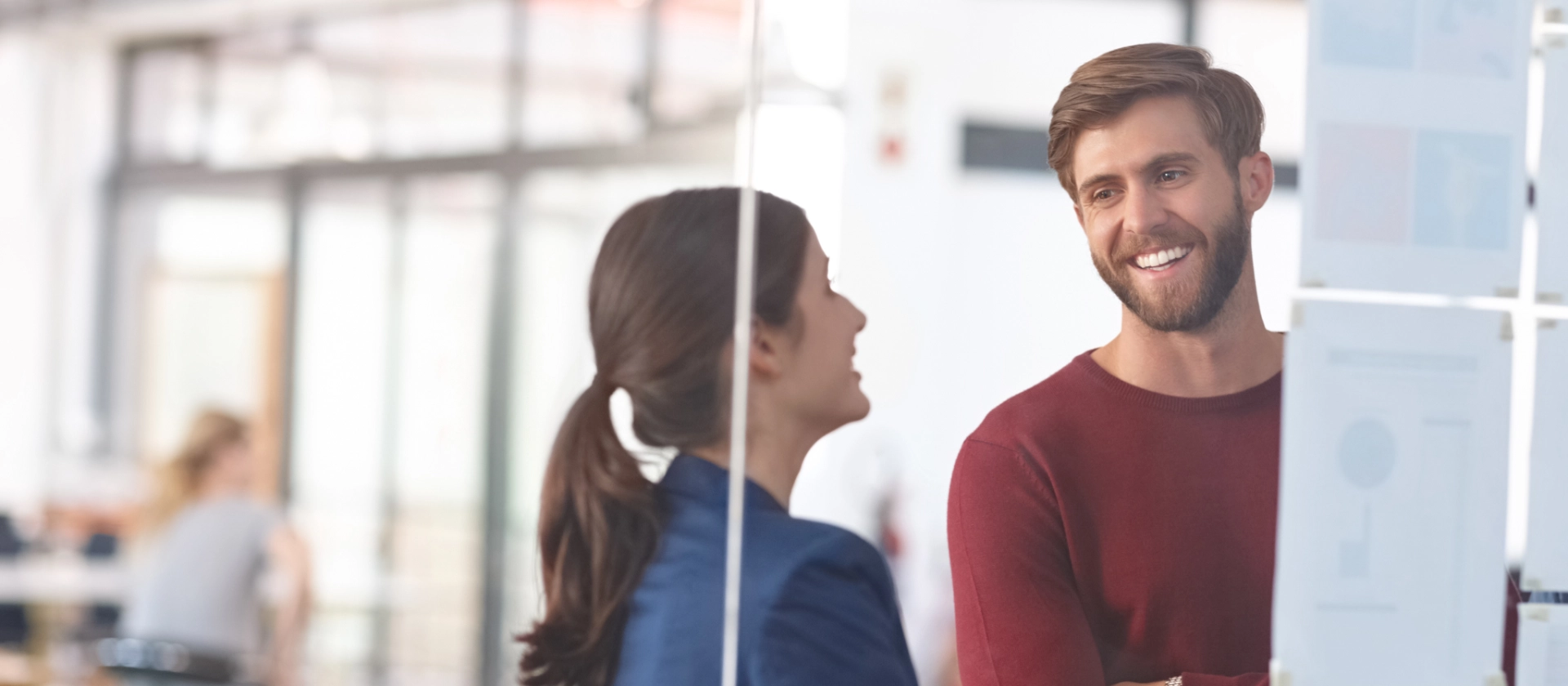 Zwei Mitarbeitende aus dem Geschäftsbereich Healthcare stehen vor einer Glaswand mit Notizen und unterhalten sich
