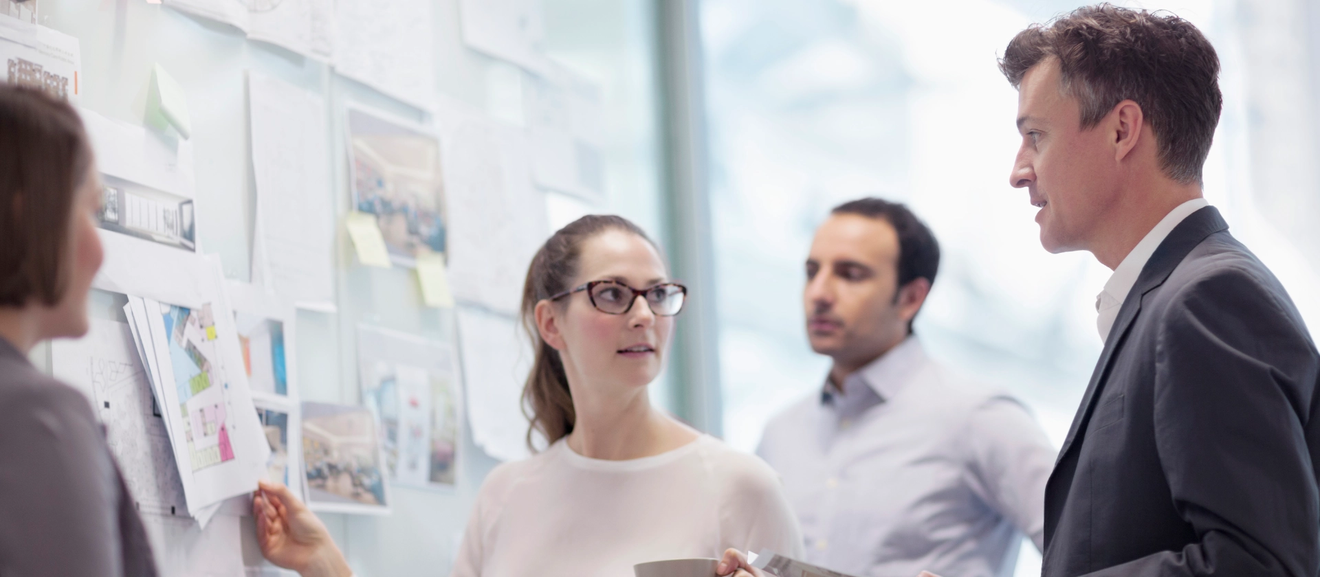 Zwei Frauen und zwei Männer aus der Geschäftseinheit Insurance besprechen sich vor einem Whiteboard mit Notizen