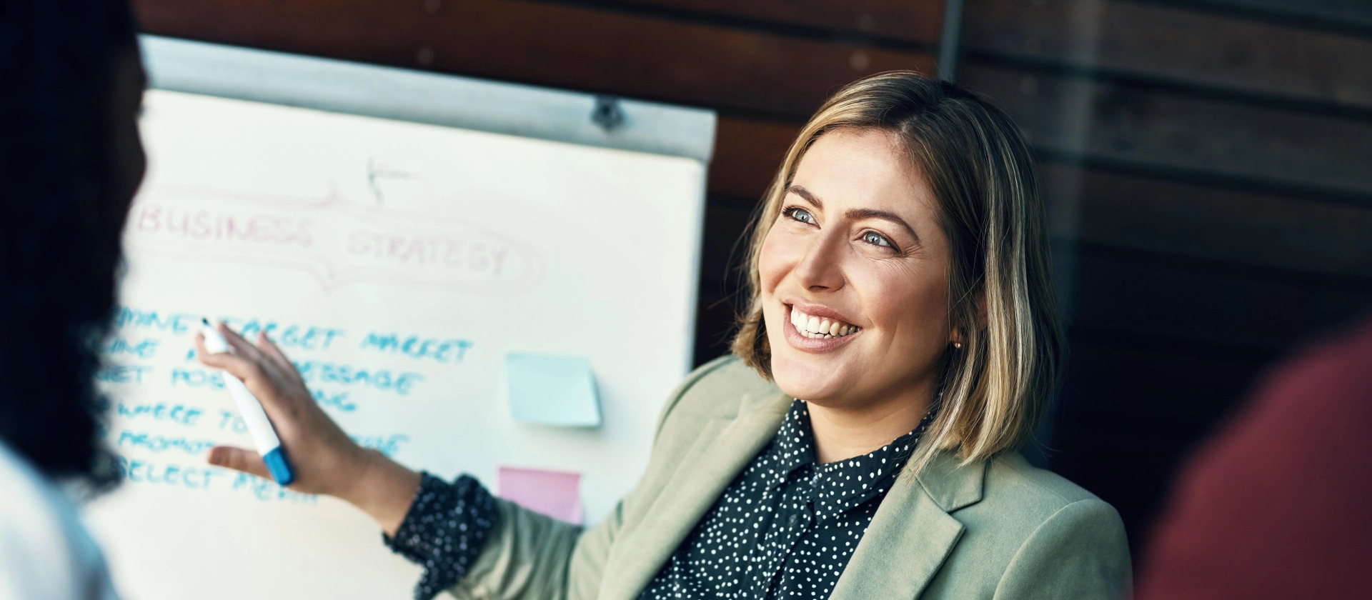 Businessfrau hält Stift und steht vor Whiteboard
