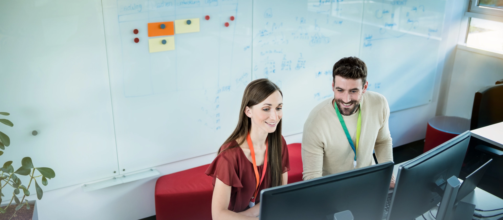 Männlicher und weibliche IT Consultant von oben an ihrem Arbeitsplatz neben einem Whiteboard